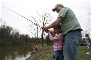 Erik Young of Perrysburg helps daughter Kelsi, 6, cast her line into Silver Lake while taking part in the park event.