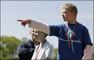 Collin Morrow points to his family after he is awarded the first-place medal for the Special Olympics' 100-meter run.