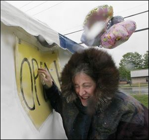 nbrn plants15P  MAY 11  2008 BLADE PHOTO BY HERRAL  LONG  Ann Pillarelli  of monroe hangs out open sign in the rain people will hopefully stop     The Monroe county  humane society plant sale  all proceeds to go to the humane society.