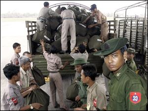 A Myanmar soldier, right, pauses and he and his colleagues unload bags of supplies aid, donated by Thai King Bhumibol Adulyadej, from a Thai military plane onto a truck at Yangon airport in Myanmar on Sunday. 