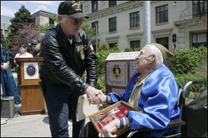 Purple Heart recipients William Sauerwein of Maumee, left, and Leo Uliczny, 91, of Toledo shake hands at a memorial honoring veterans who were awarded the medal. The granite monument, in background, was unveiled at the Civic Center Mall in Toledo.