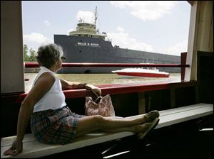 Sitting in the Sandpiper on a cruise of the Maumee River, Brenda Haag of Toledo views boats past and present: the Willis B. Boyer museum ship in the background and a modern vessel passing by in front of it.
