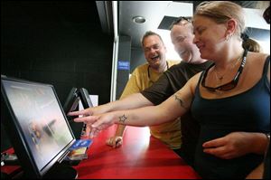 Matt Walker, left, Mark Blundell, both of Poole, England, and Marie Boxall, of Norwich, look at pictures of themselves riding a roller coaster at Cedar Point.