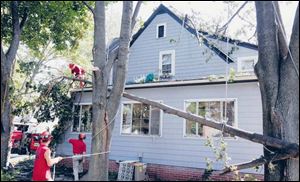 Workers from All Seasons Tree Care remove storm-damaged trees.
