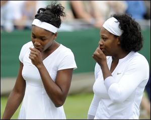 Venus Williams, left, and her sister, Serena, confer during their doubles victory over Bethanie Mattek and Sania Mirza.