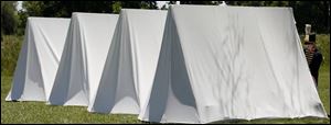 Anya Harner of Bowling Green, at far right, fastens her tent to meet up with her company at Fort Meigs yesterday.