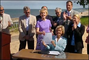 Michigan Gov. Jennifer Granholm, seated, holds the Great Lakes compact with state Sen. Patricia Birkholz after signing it on the shores of Lake Michigan at Saugatuck.