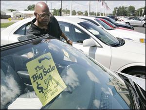 Salesman Zack Clark prepares a sign in a car for sale at Grogan
Towne Chrysler-Dodge in Toledo.