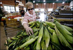 Bonnie Elwell, of Toledo, selects from a bin of locally grown corn at Monnette's on Secor Road in Toledo.