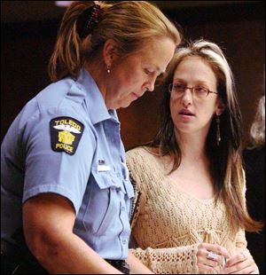 Rachel Richardson, right, confers with Shirley Guardiola of the Toledo police during a court proceeding. Ms. Richardson and her business partner coach clients on legal options.