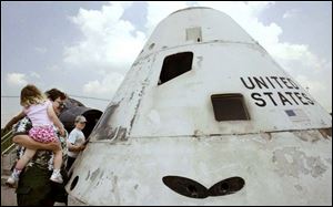 Gary Seils, a visitor from Chicago, with daughter Abigail, 3, and son Stephen, 12, peeks into the museum's Apollo command module mockup. The museum, owned by the Ohio Historical Society, is open daily except for Mondays.<br> 
<img src=http://www.toledoblade.com/graphics/icons/photo.gif> <font color=red><b>VIEW</font color=red></b>: <a href=