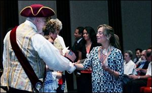 Michael Lieber, Sylvania s town crier, congratulates
Fatma El Sweafi Amer, a native of Egypt, on becoming a U.S. citizen after naturalization ceremonies held at the Fifth Third Center at One SeaGate in downtown Toledo. Ms. Amer was one of 28 people yesterday who took the oath of citizenship administered by U.S. District Court Judge Jack Zouhary.
