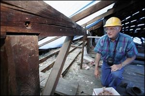 Tony Urbas, a volunteer with Friends of the Lathrop House, checks the attic while the roof is being replaced.