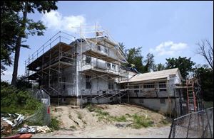 Crews from Mosser Construction Inc. work on the scaffolding-encased Lathrop House.