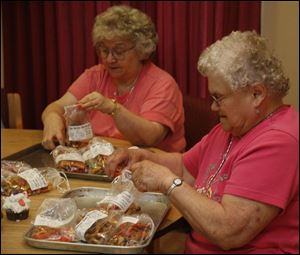 Volunteers Wanda Taylor and Jackie Curtis load up doggie bags of 'nun-better' dog biscuits for sale at the festival. Sacred Heart cooks stir up the toothsome treats just once a year. 