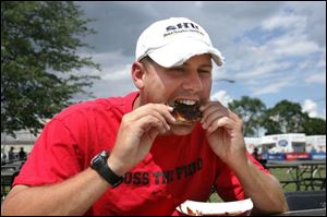 Jason Whitacre, of Holland takes a bite of ribs. He showed up early yesterday at the Lucas County Fairgrounds and plans to come back today. 