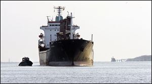 A tug guides a freighter to a Maumee River dock, where shipping is dependent on frequent dredging of the channel.