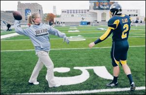 Equipment crew member Mallory Hensley throws
a ball past punter Bill Claus during a drill at the UT stadium.