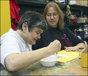 Karen Lewis, in foreground, works with adult service provider Tammy Wood on making a glitter Christmas ornament in the 'Kan Du Studio' at the Blanchard Valley Center. The agency has regained its accreditation from the Ohio Department of Mental Retardation and Developmental Disabilities after losing it in 2007.