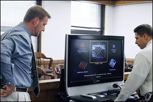 Eric Zatko, left, program manager for the court's integrated justice system of Lucas County, and Michael Jordan of the Corrections Center of Northwest Ohio set up a video monitor.