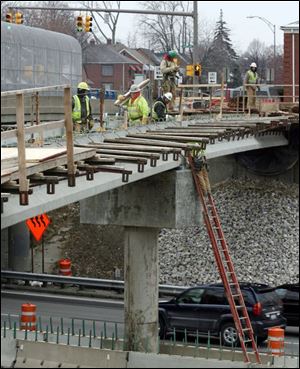 Workers build a utility bridge over I-475 just west of the Douglas Road overpass. The project means traffic delays in the area.