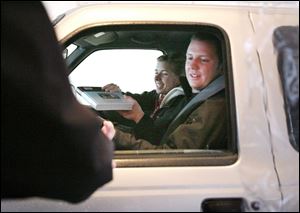 Dave Malone, right, and Jackie Switzer turn in books to Budgetext employee Kendall Cottongim at a drive-through book buy-back station on Owens Community College s Perrysburg Township campus. Jerry Mohr, owner of Budgetext, which operates the campus bookstore, said about 260 vehicles used the service yesterday, returning books from Owens, the University of Toledo, and Bowling Green State University. According to Mr. Mohr, the entire transaction takes only three or four minutes.  They just come zipping through here,  he said.  The kids just love this, and it s perfect for commuters. 