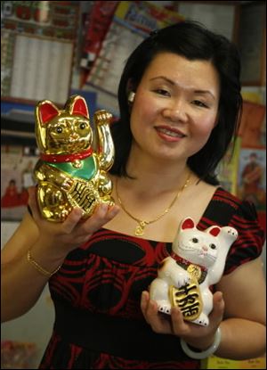 Houng Dhar with her Maneki Neko, lucky cats, an Asian good luck tradition.