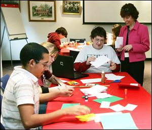 NBRE cards18p  Jesus Romero, 16, left, and Lexie Sroga (cq), 14, work on their cards while Steven Ackerman, 17, shows his to teens' librarian Pam Ade. The teens are students at Rossford High.  Students from Rossford Junior and High Schools create holiday cards for recipients of Meals-on-Wheels in a program for teens at the Rossford Public Library in Rossford, Ohio on December 11, 2008. The Blade/Jetta Fraser