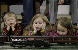 Jack Dieter, 2, left, and his sisters, Sophia, 6, and Irene, 5, keep a close eye on the passing O-gauge trains owned by Bill Frankman of Greenville, Ohio. The three Maumee children were with their parents, Aaron and Kristy Dieter, yesterday.