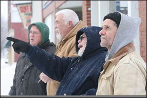 Steve Dillon, left, Steve Hilvers, Bob Van Atta, and Howard Barnett watch Findlay firefighters extinguishing a blaze that consumed buildings at 209-211 N. Main St. 