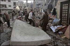 Palestinians shift through the debris after an Israeli airstrike yesterday in Gaza City. Israeli officials say they will not withdraw from Gaza until Hamas agrees to a long-term cease-fire. 