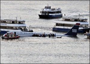 Passengers wait on the wings of a US Airways Airbus to board boats after the jetliner safely landed on the Hudson River. 