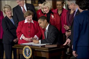 Lilly Ledbetter watches behind President Obama as he signs the Lilly Ledbetter Fair Pay Restoration Act in the White House. Sen. Barbara Mikulski (D., Md.) is at his left.