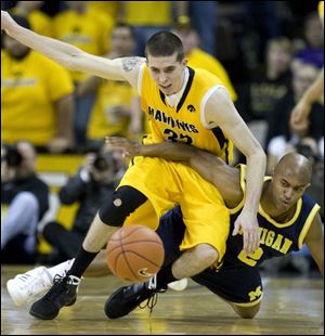 Iowa s Jake Kelly, left, and Michigan s C.J. Lee fight for the basketball. Kelly had career highs of 23 points and nine assists.