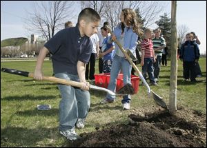 NBRS woodland29p  04/24/09  The Blade/Dave Zapotosky Caption: Cruz Gongora, 6, a first grader at Frank Elementary School, left, puts a shovel of dirt on the official new Arbor Day tree during the 25th anniversary Arbor Day celebration in Woodlands Park in Perrysburg, Ohio, Friday, April 24, 2009.  The tree is a London Plane. Summary: 25th anniversary Arbor Day celebration at Woodlands Park Shelter House in Perrysburg.