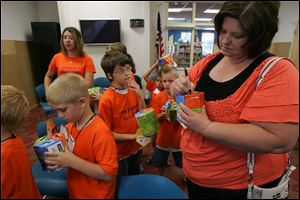 Seth Casey, 8, left, and Austin Bailey, 11, wait to have their names written on their Moonjar Moneyboxes by Toddler School Director Jenny Lewis at Lagrange Branch Library. 