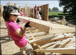 Above, Michelle Thompson of the Cass Road Baptist Church in Maumee helps erect a wall as the Maumee Valley Habitat for Humanity builds a five-bedroom ranch house on Ansonia Street in Oregon. The project is to be finished this month.  Five area churches are helping to complete the task. Below and bottom: Vickie Shutters of Swanton and Bill Forsee of Christ Presbyterian Church in Toledo join the group.