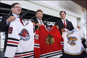 Mark Bernard of the Chicago Blackhawks, left, Walleye coach Nick Vitucci, middle, and Walleye general manager Joe Napoli hold jerseys after announcing an affiliation agreement between the two teams.