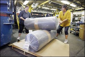 Angie Earl, left, and Laura Robinson pack vinyl mats at Ludlow Composites Corp. Gov. Ted Strickland lauded the Fremont-based company, which exports to 50 countries on five continents.