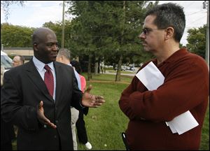 Toledo mayoral candidate Mike Bell, left, talks to city resident Cliff Warstler outside the Toledo Fire Fighters Federal Credit Union near Fire Station 23 on West Laskey Road yesterday.