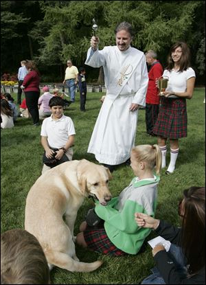 Deacon Tom Sheehan blesses Newman, held by owner Helen Waldie, 10, a student at Sylvania
Franciscan Academy, during the annual Blessing of the Animals. Yesterday's ceremony at Lourdes
College celebrated the feast of St. Francis and included the blessing of dozens of bins of worms
— which contribute to our well-being, the deacon said.