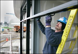 BIZ build18p 10/15/09 The Blade/Dave Zapotosky Caption: Ryan Endicott of Interstate Commercial Glass and Door installs weatherstripping for windows at the business incubator building under construction on the University of Toledo campus in Toledo, Ohio, Thursday, October 15, 2009. Summary: Workers building a business incubator on the main campus of the University of Toledo