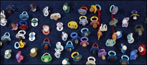 Some of the 600 pacifiers from young patients hang on a wall in their Maumee office.