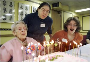 the blade/dave zapotosky Freda Sackett blows out her candles with help from niece Carol McCallister, center, and great-niece Kira McCallister during her 100th birthday celebration at St. Paul's Lutheran Church in downtown Toledo. The beverage for the party was tea.