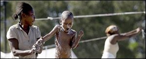 A mother cleans her son in a makeshift tent city near the National Palace on Saturday, Jan. 16, 2010 in Port-au-Prince. 