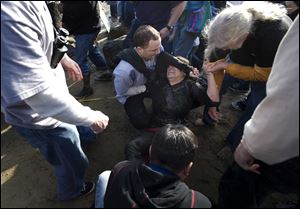 A woman grimaces in pain as bystanders attempt to comfort her until emergency personnel arrive. The woman was among several hurt at the Mavericks Surfing Contest.