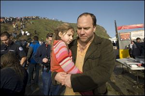 Vince Perrini carries his daughter, Sofia, away from the scene of mayhem as spectators were struck by rogue waves at a surfing contest in California. The father and daughter were swept into the sea by one wave.