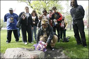 Wendy Robinson, whose son, Donnie, was murdered, lays flowers on a memorial as other family members of murder victims watch on the Lucas County Courthouse lawn. The Parents of Murdered Children and the county prosecutor's office organized the vigil last evening in observance of Victims' Rights Week.