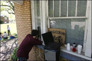 Lance Crandall of the Toledo Foreclosure Defense League speaks to the barricaded Keith Sadler through a porthole in his house.