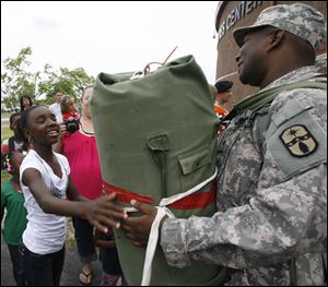 Spc. Lorenzo Oliver of the Ohio National Guard's 1483rd Transportation Company is welcomed home by family member Larshell Himon, 13, of Toledo. About 180 personnel from the company, which is based in Walbridge, were greeted by friends and relatives yesterday at Owens Community College after a one-year deployment to support Operation Iraqi Freedom efforts in the Middle East.